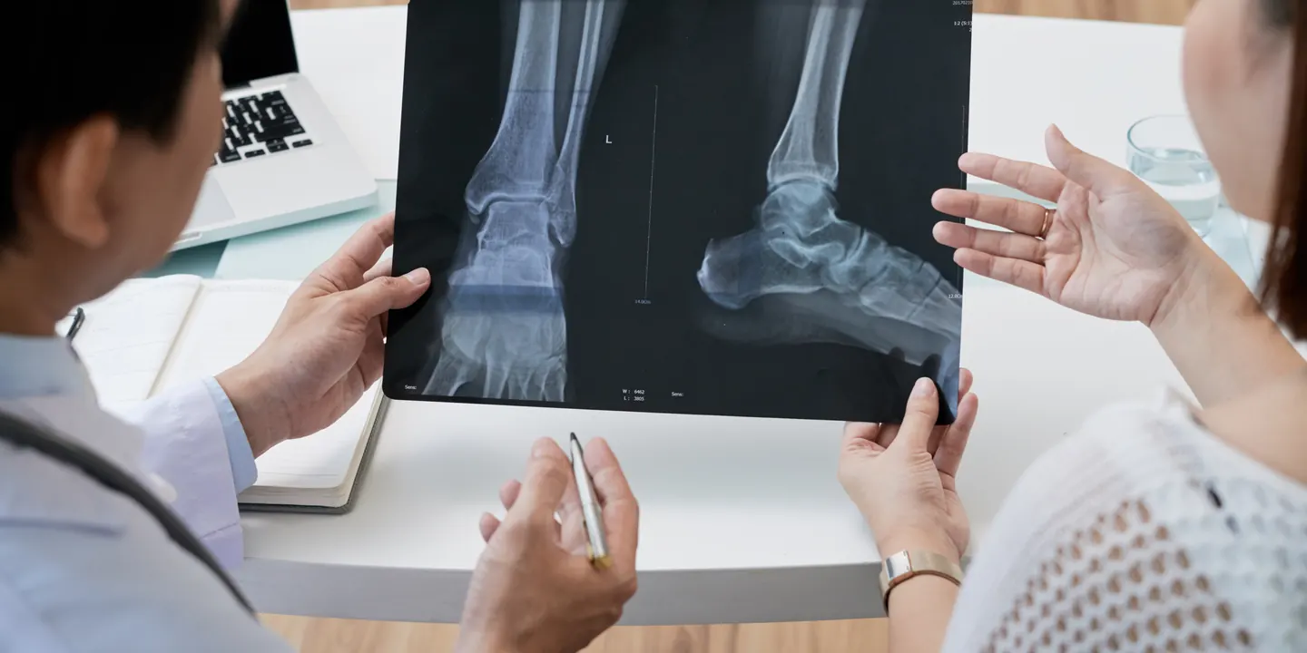 Surgeon and patient reviewing foot and ankle X-rays together at a first consultation