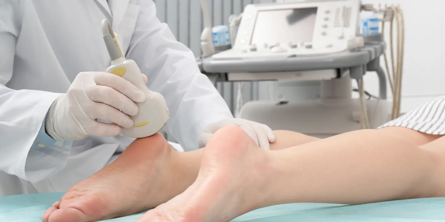 Clinician holding a probe against a patient’s heel in clinic, with the treatment machine alongside