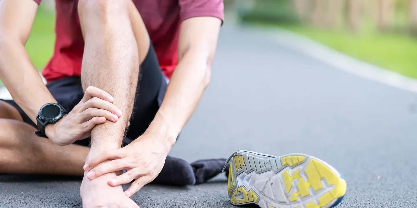 Runner stopping on the road to hold a painful foot, an early warning sign of a stress fracture