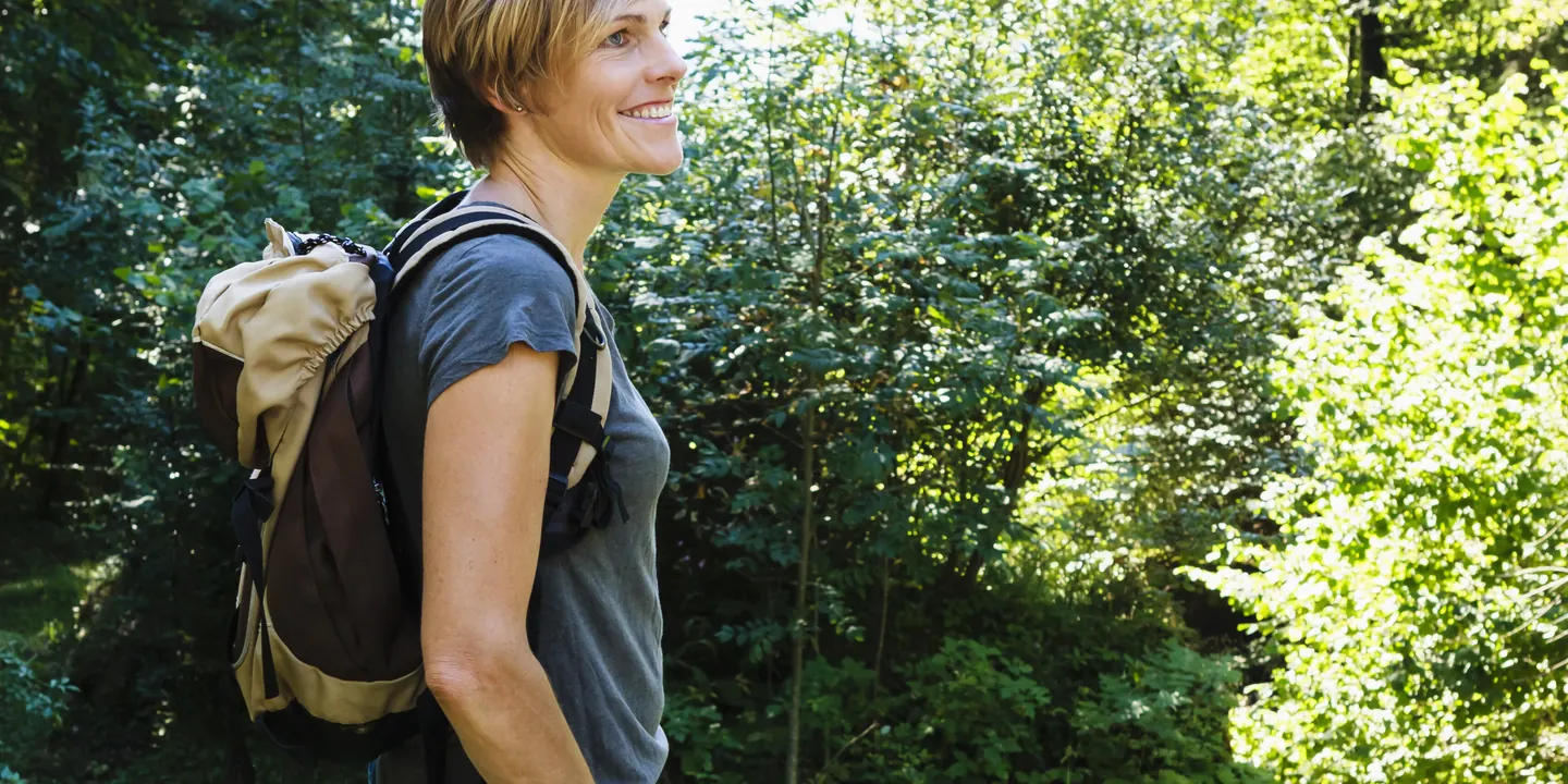 Woman hiking a woodland trail in supportive walking boots on a summer day